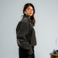 Woman wearing a green jacket and black pants against a plain background