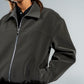 Person wearing a dark gray jacket with a plain background