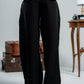 woman wearing a black pants against a neutral background
