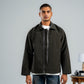 Man wearing a dark jacket over a white shirt with a gray background