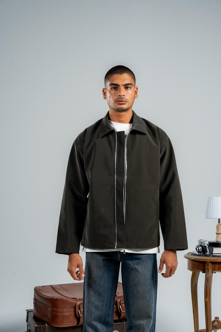 Man wearing a dark jacket over a white shirt with a gray background