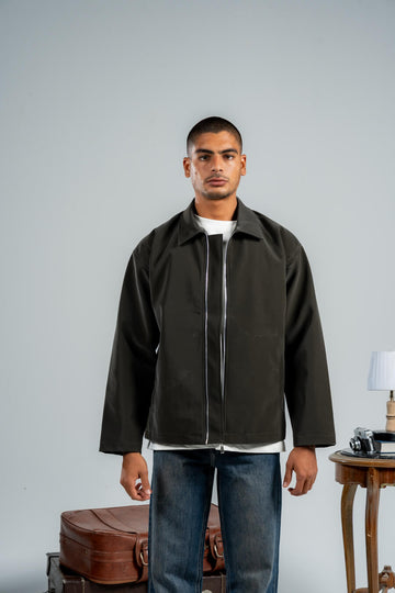 Man wearing a dark jacket over a white shirt with a gray background