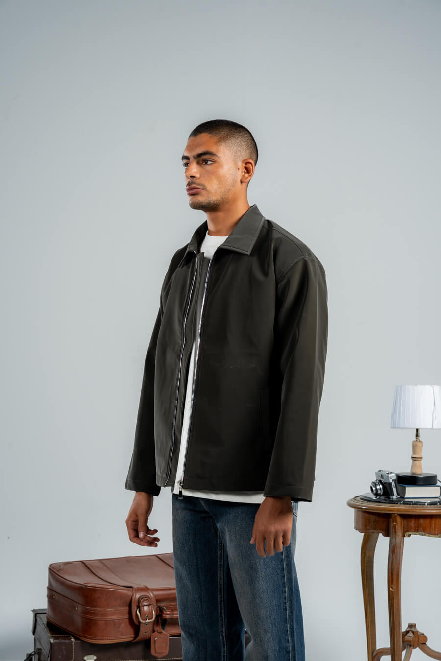 Man wearing a dark jacket over a white shirt with a gray background