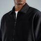 Man wearing a black jacket against a gray background