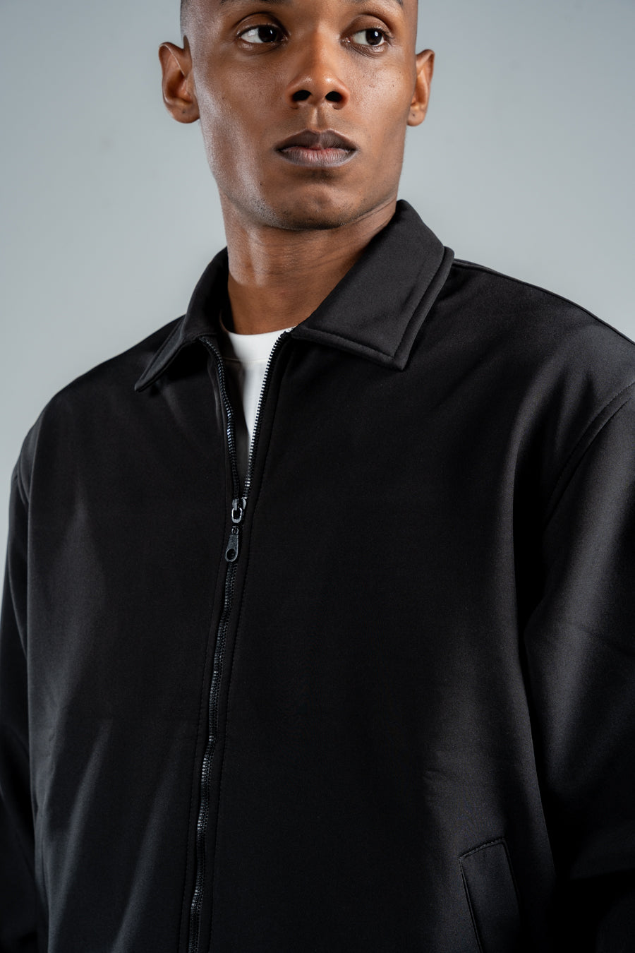 Man wearing a black jacket against a gray background