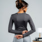 Woman wearing a gray long-sleeve top and gray pants against a plain background