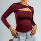 Woman wearing a burgundy long-sleeve top with cut-out design on a gray background