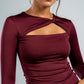 Woman wearing a burgundy long-sleeve top with cut-out design on a gray background