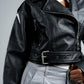 Person wearing a black leather jacket with a gray background