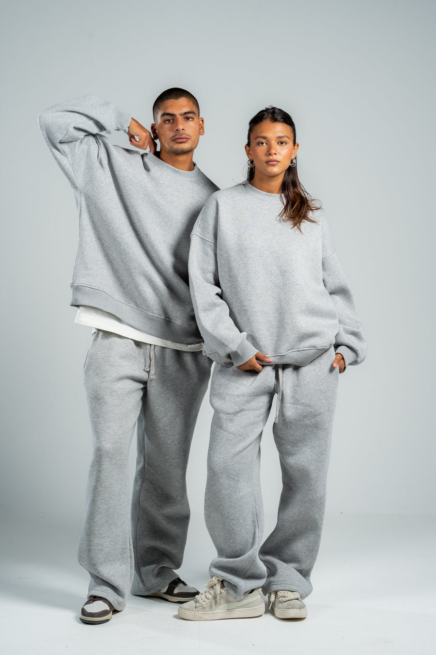 Two people wearing matching gray sweatshirt and pants sets on a plain backgroundshop_this_look_86DbjN