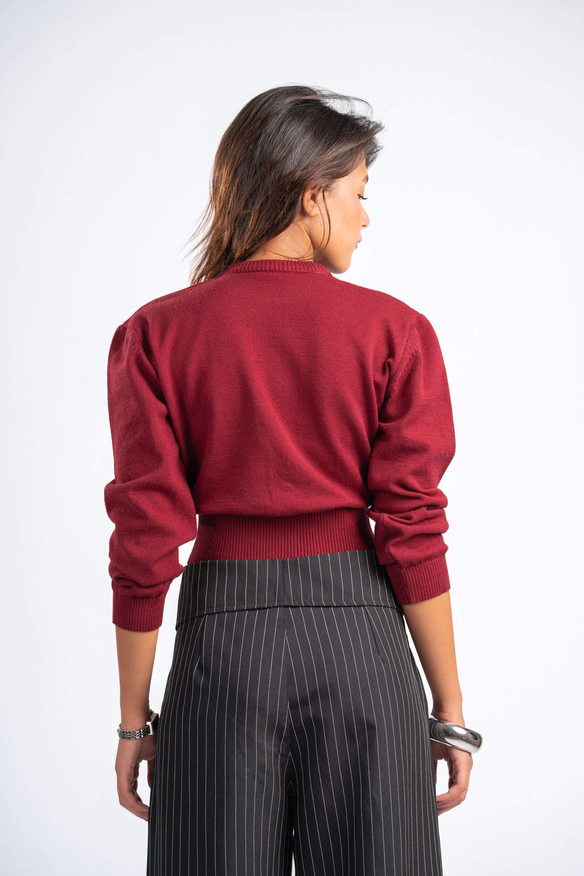 Person wearing a red sweater and black pinstripe pants on a white background