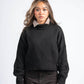 Woman wearing a black sweater with patterned cuffs and collar against a white background