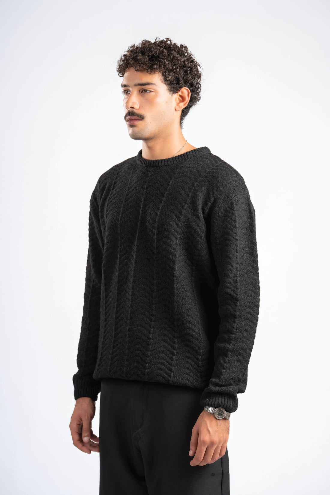 Man wearing a black cable knit sweater on a white background