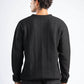 Person wearing a black sweater with a textured pattern on a white background