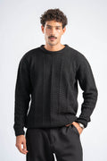 Man wearing a black cable knit sweater on a white background