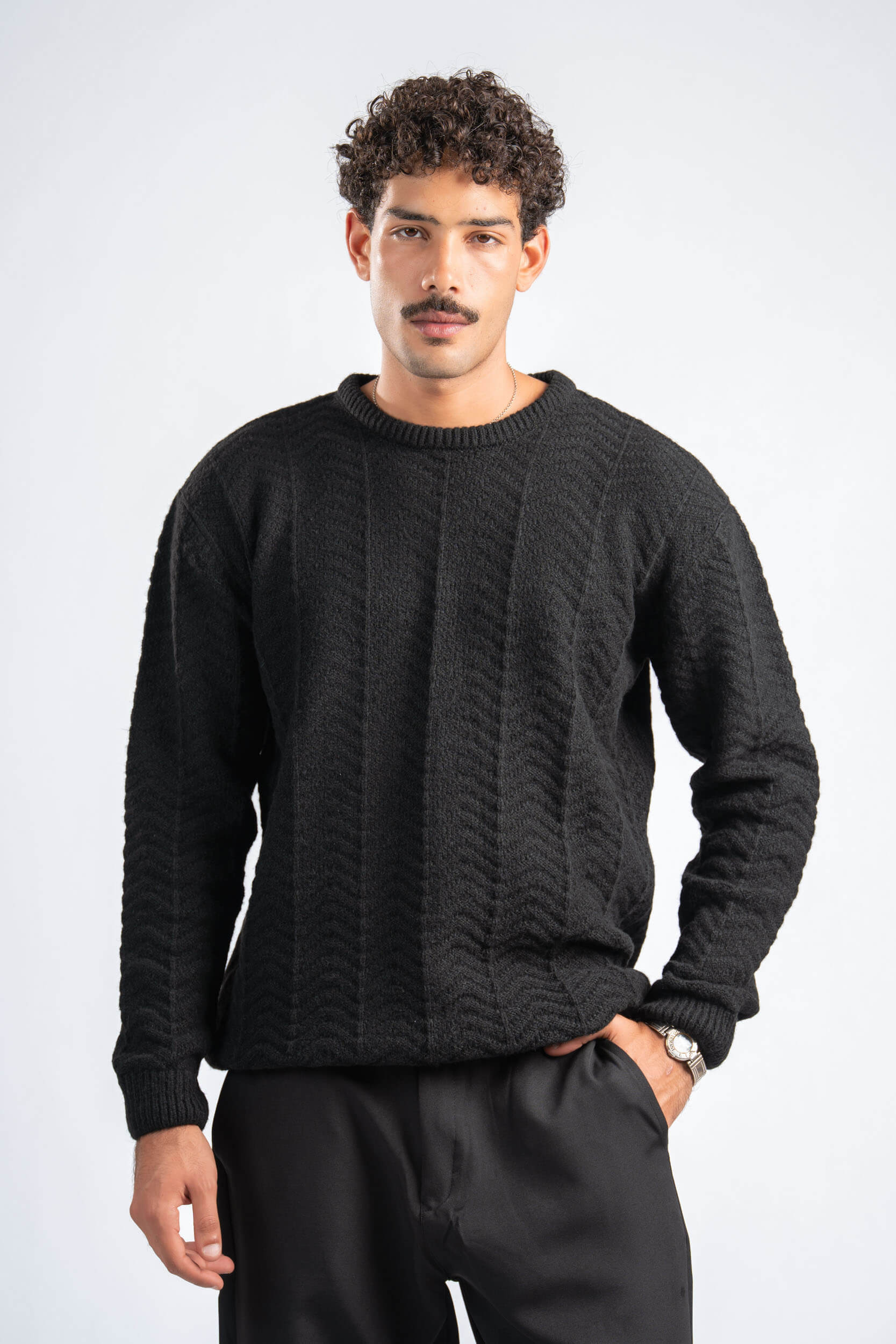Man wearing a black cable knit sweater on a white background