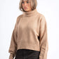 Woman wearing a beige sweater on a white background
