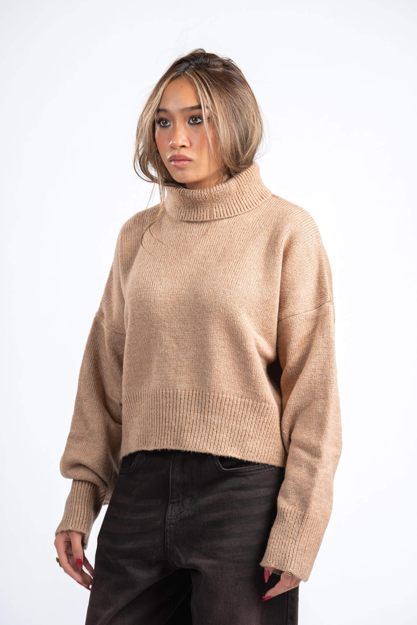 Woman wearing a beige sweater on a white background