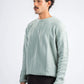 Man wearing a light green knitted sweater against a white background