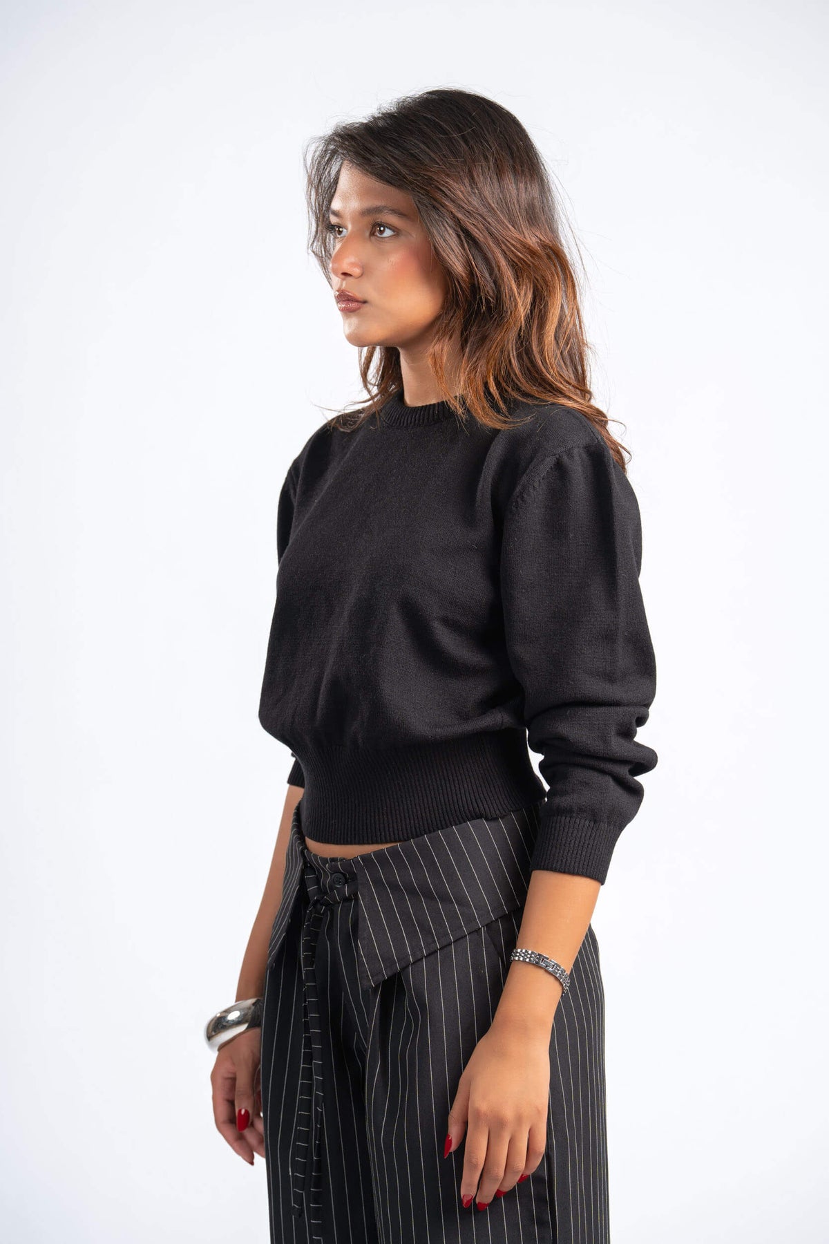 Woman wearing a black sweater and pinstripe pants on a white background