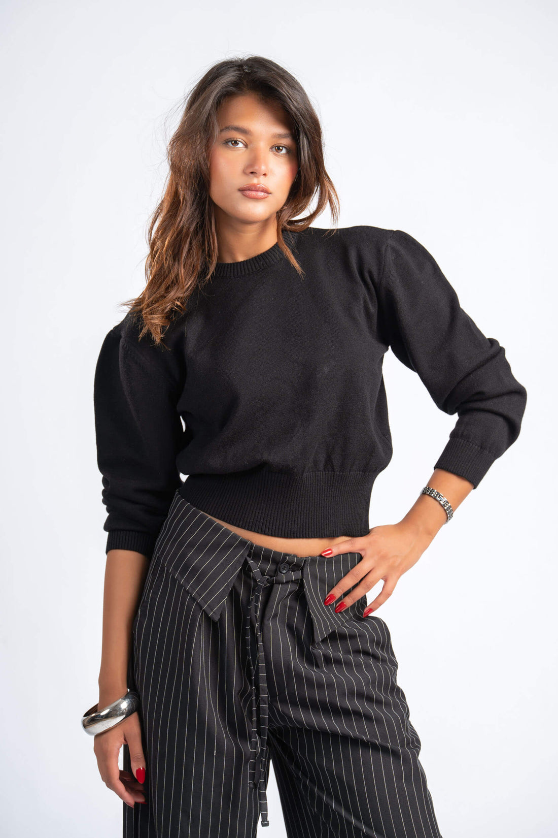 Woman wearing a black top and striped pants on a white background