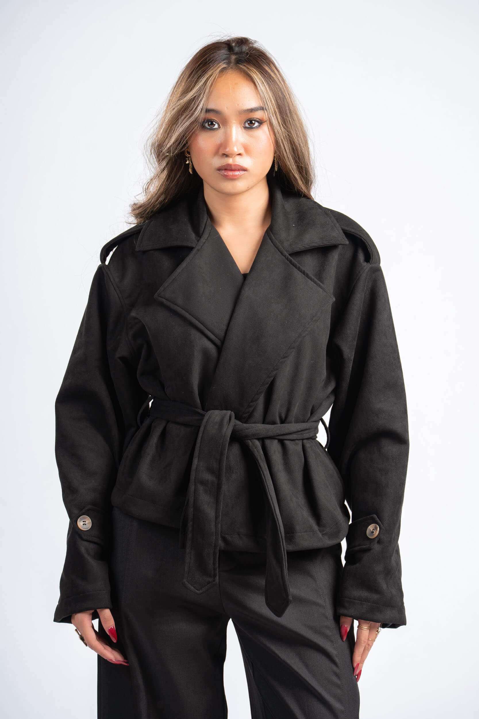 Woman wearing a black coat with a belt on a white background