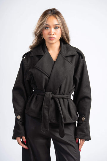 Woman wearing a black coat with a belt on a white background
