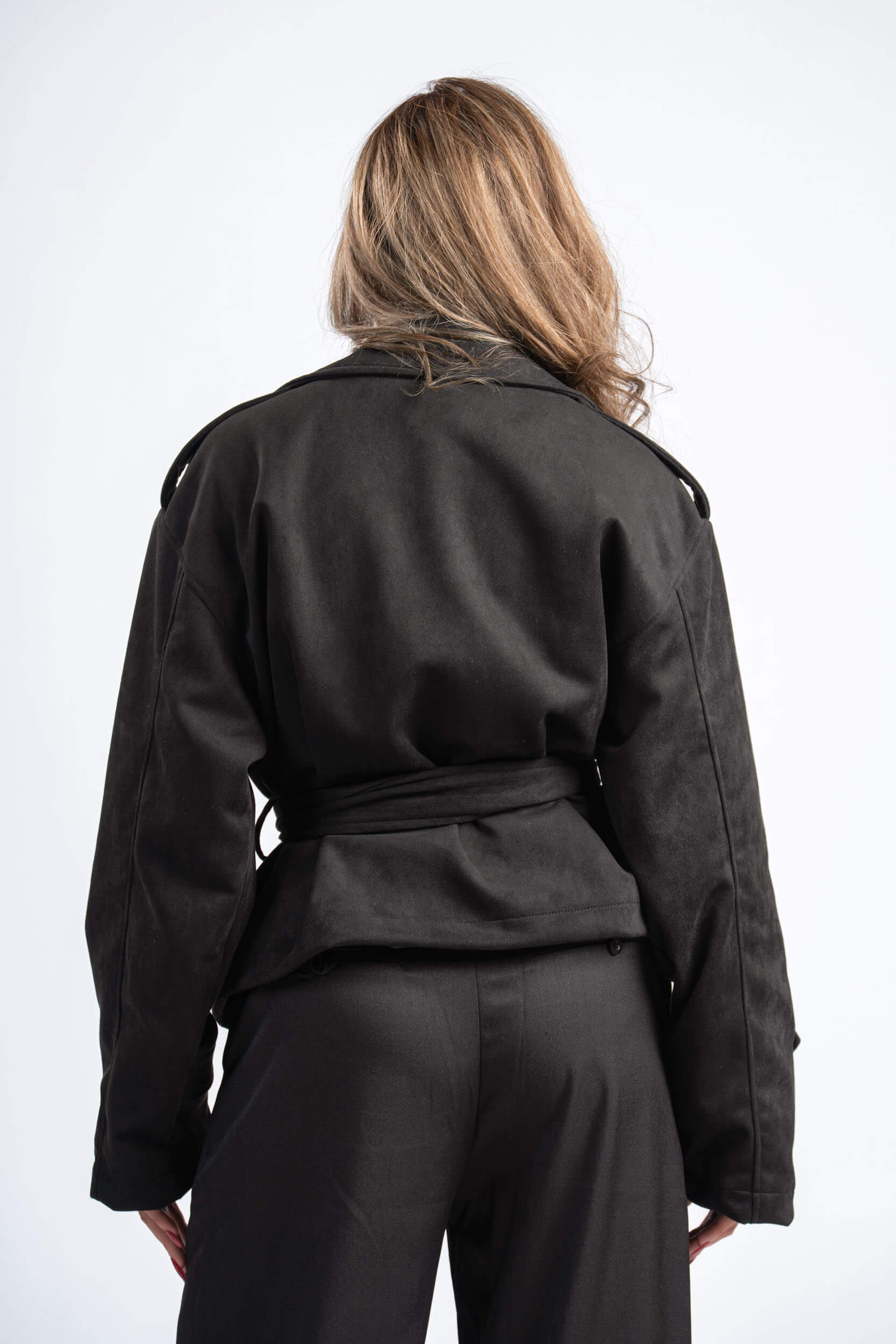 Person wearing a black jacket and pants on a white background