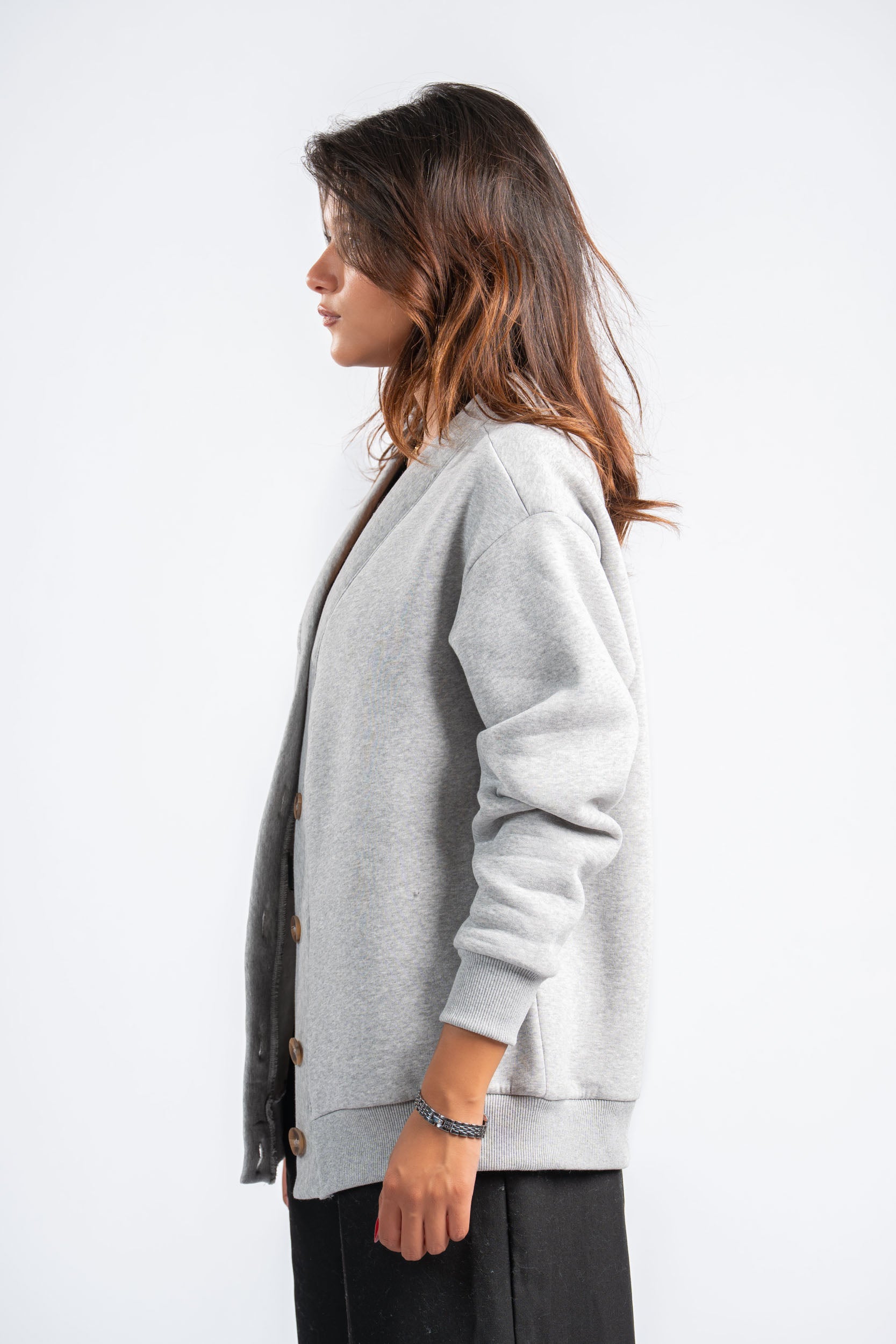 Woman wearing a light gray cardigan over a black top on a white background