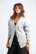 Woman wearing a light gray cardigan over a black outfit on a white background