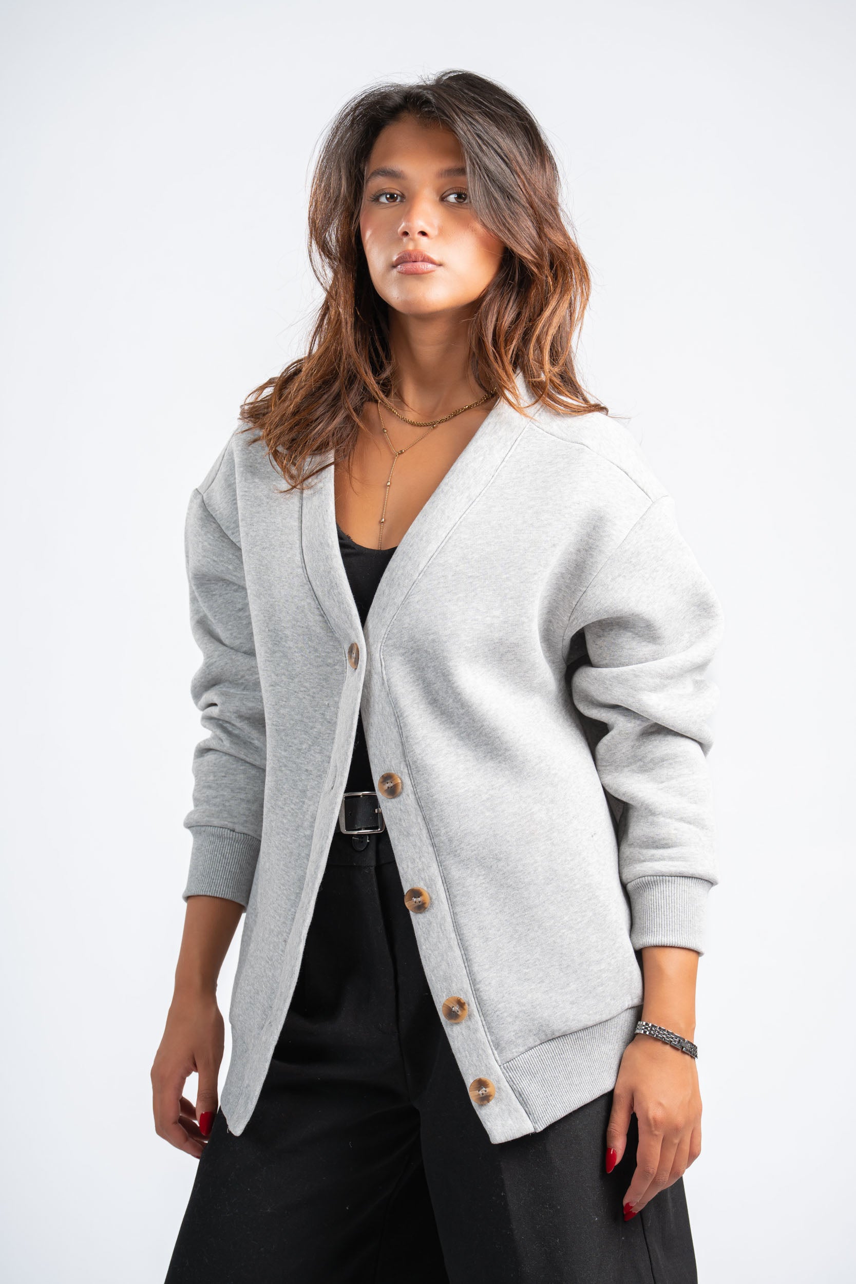 Woman wearing a light gray cardigan over a black outfit on a white background