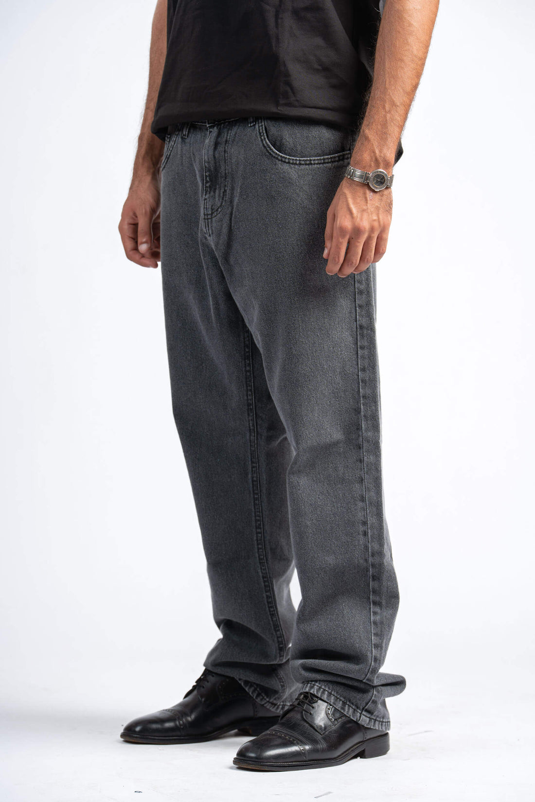 Person wearing gray jeans and black shoes on a white background
