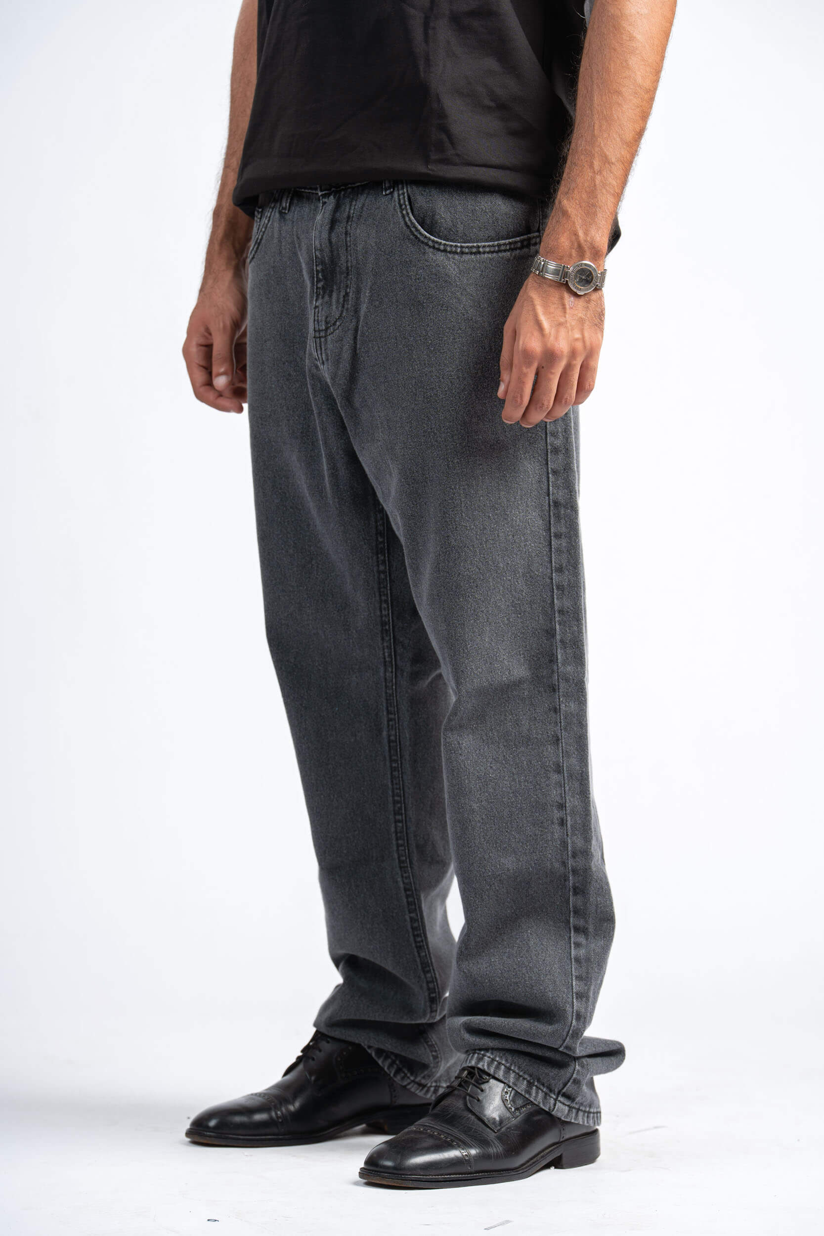 Person wearing gray jeans and black shoes on a white background
