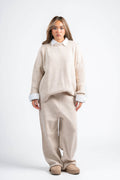 Woman wearing a beige sweater and pants set on a white background