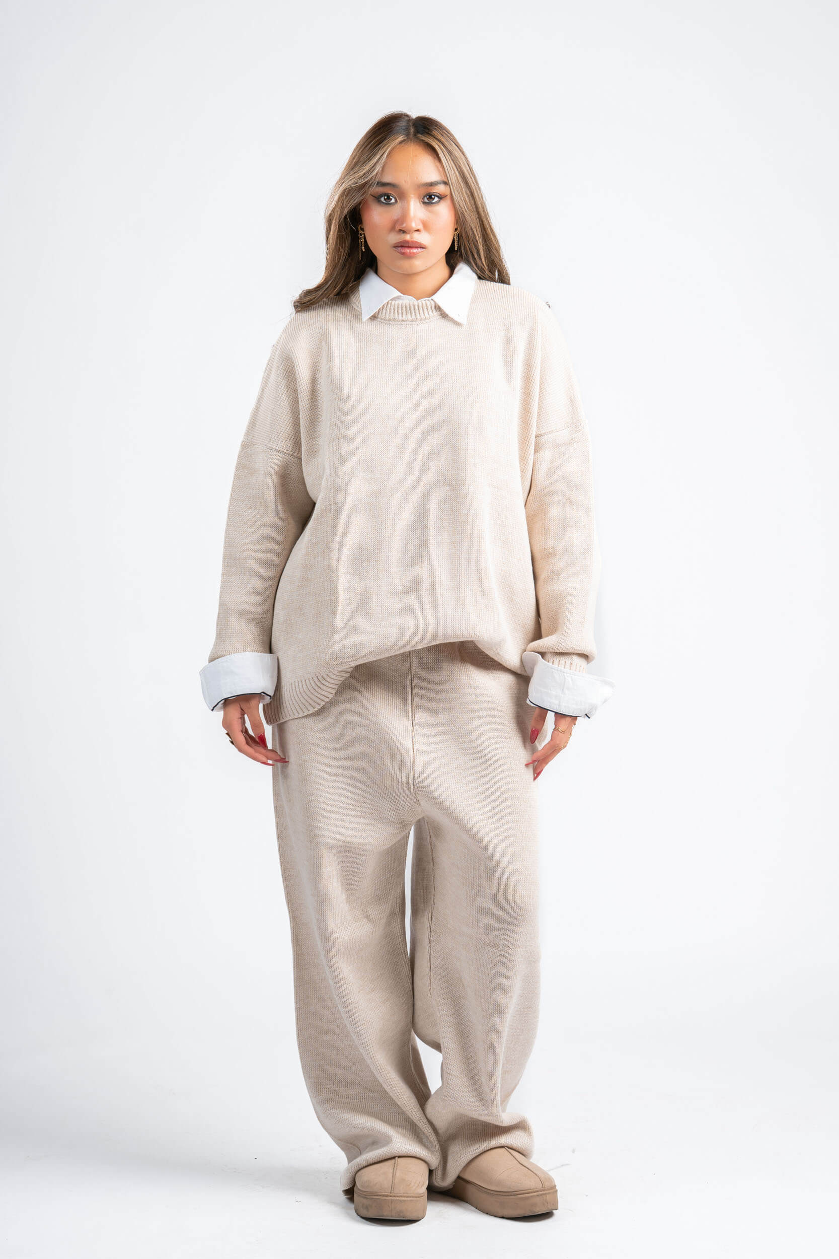 Woman wearing a beige sweater and pants set on a white background