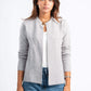 Woman wearing a gray cardigan over a white shirt and blue jeans on a white background