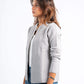 Woman wearing a gray cardigan over a white shirt with blue jeans on a white background