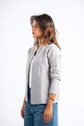 Woman wearing a gray cardigan over a white shirt with blue jeans on a white background