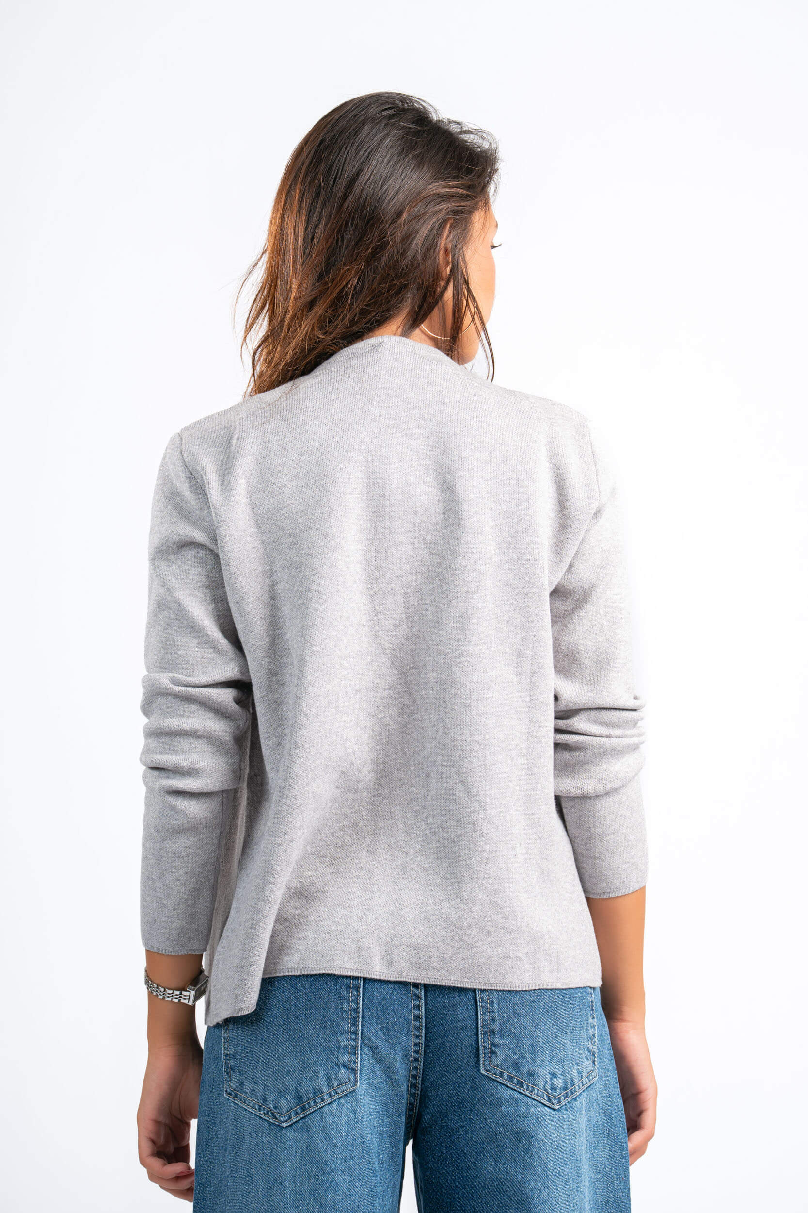 Person wearing a gray sweater and blue jeans on a white background