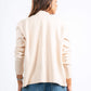 Woman wearing a beige sweater and blue jeans on a white background
