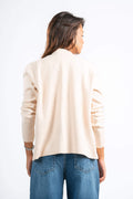 Woman wearing a beige sweater and blue jeans on a white background