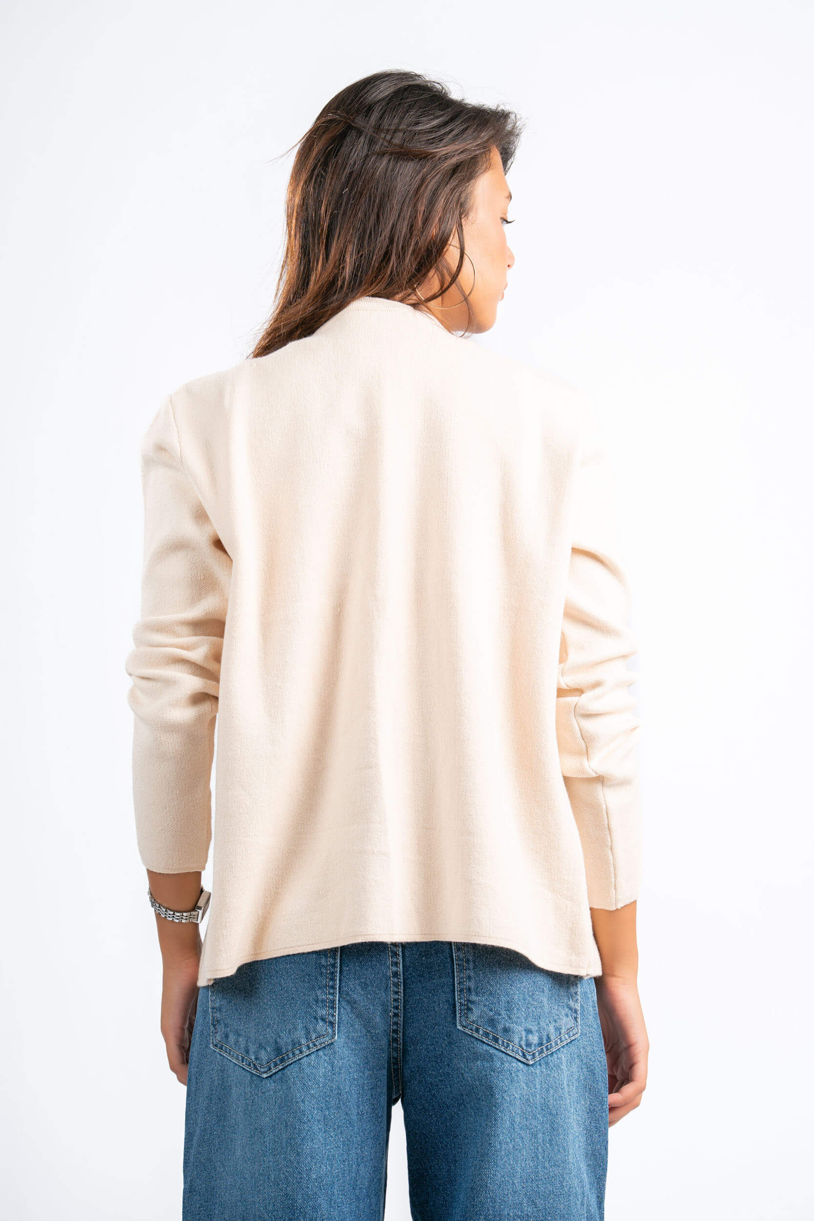 Woman wearing a beige sweater and blue jeans on a white background