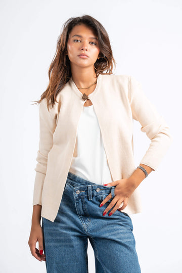 Woman wearing a beige blazer, white top, and blue jeans on a white background