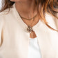 Close-up of a person wearing a beige cardigan and gold necklace with a white shirt underneath.