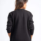 Person wearing a black sweater and blue jeans on a white background