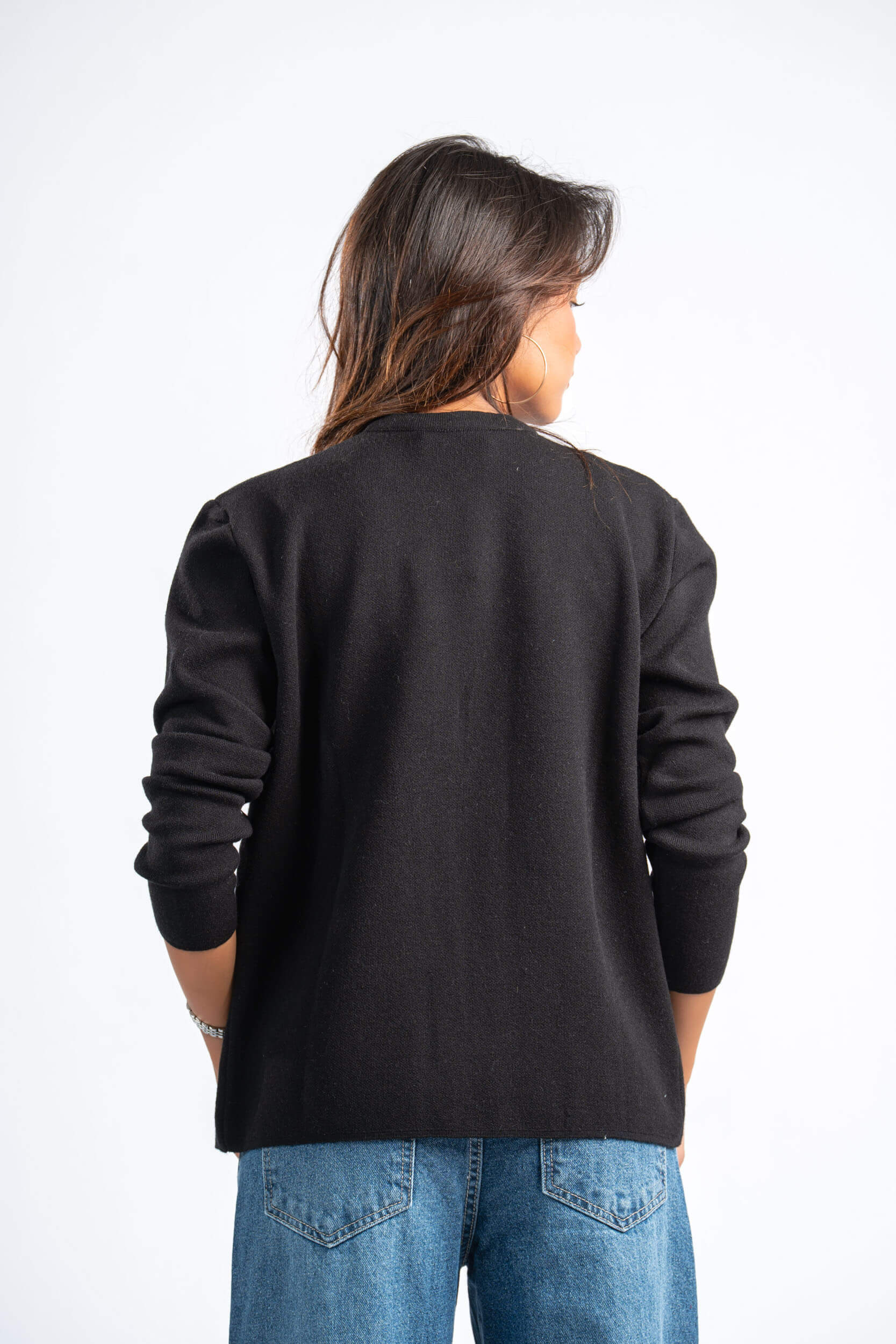 Person wearing a black sweater and blue jeans on a white background