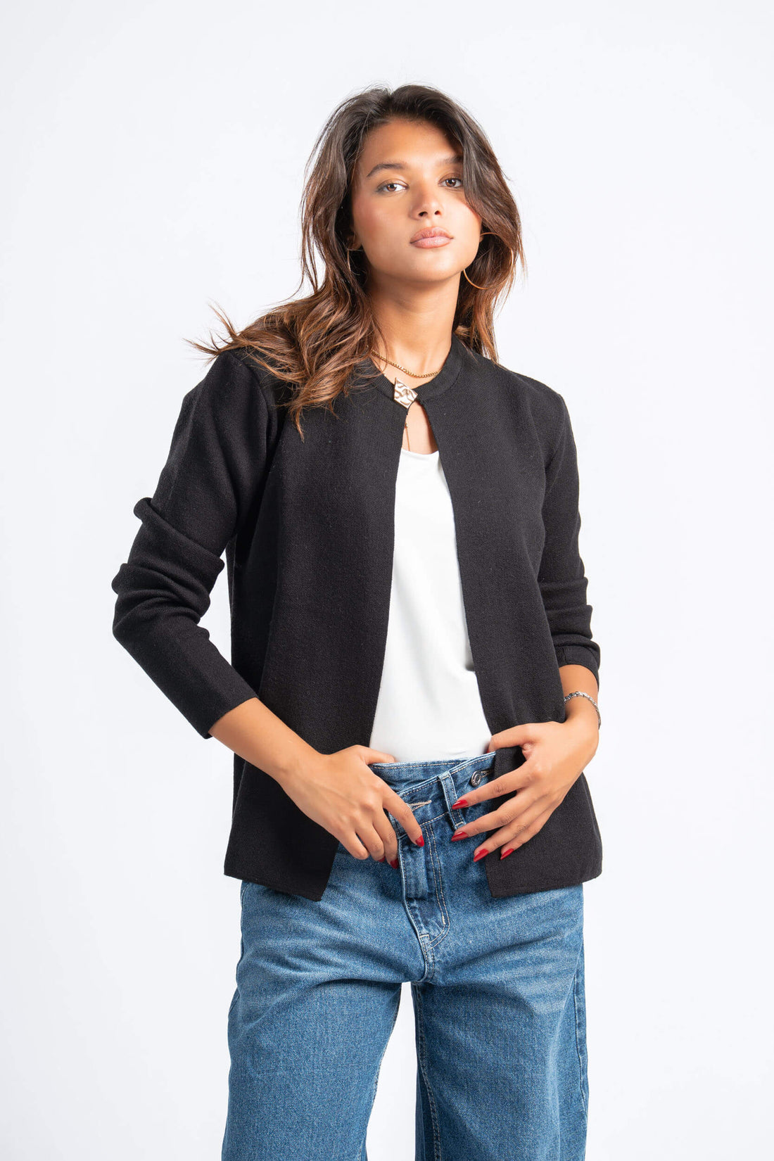 Woman wearing a black jacket, white shirt, and blue jeans on a white background