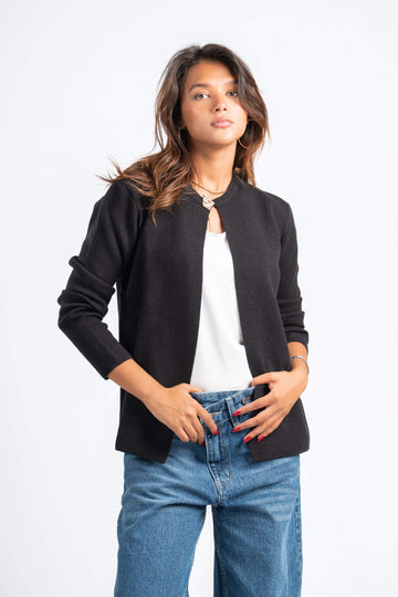 Woman wearing a black jacket, white shirt, and blue jeans on a white background