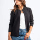 Woman wearing a black jacket, white shirt, and blue jeans on a white background
