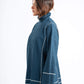 Woman wearing a blue ribbed sweater with white piping on a white background